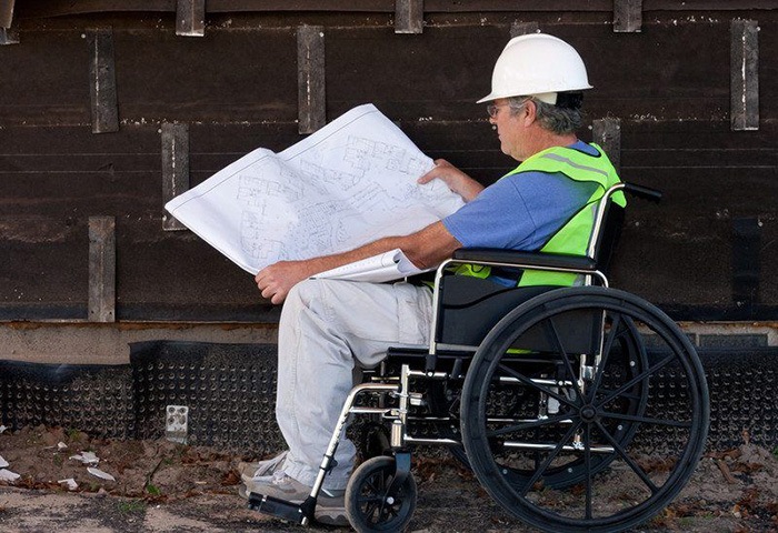 一个坐在轮椅上的人正在阅读蓝图，这是残疾人工作的一个例子
