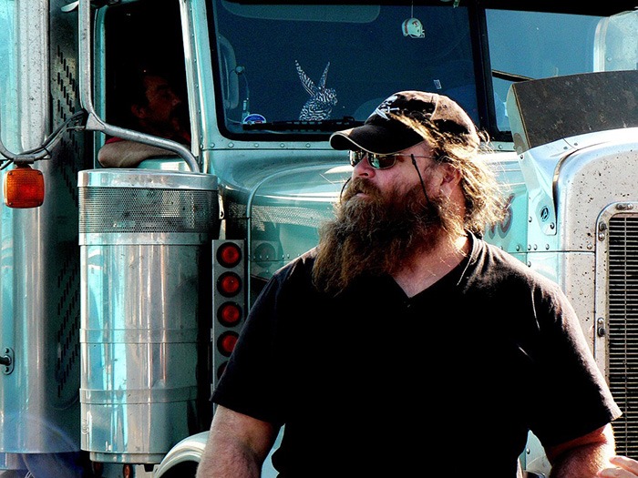 大胡子男子站在一辆卡车前，作为有犯罪记录的人工作的例子
