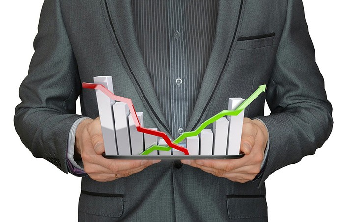 Man in a suit holding a bar graph in both hands representing economic data