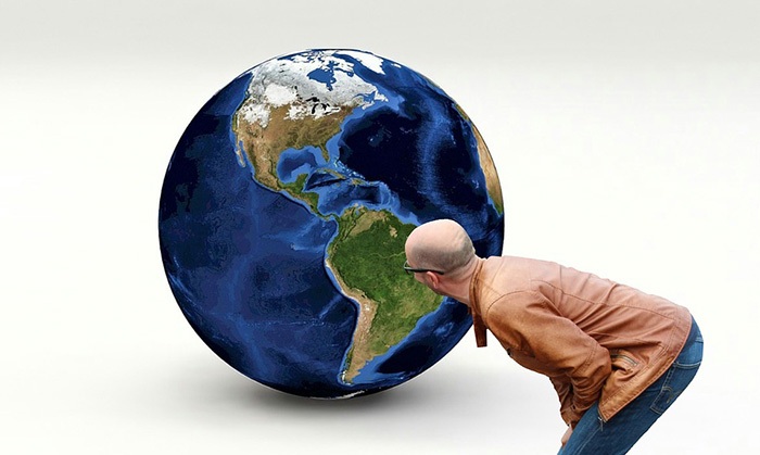 Man in leather coat staring at a large globe on the floor as an example of jobs for geography majors