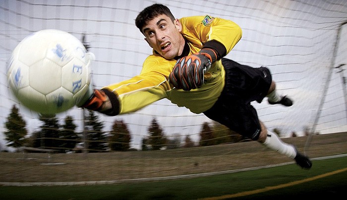 Photo of a soccer goalie diving for a ball as an example of writing about sports