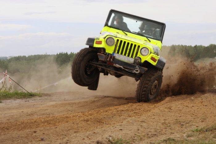 yellow jeep taking a corner fast on a dirt road almost falling over representing the best adventure tour affiliate programs