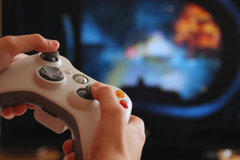 两只手和一个游戏控制器的图像，背景是一个失焦屏幕