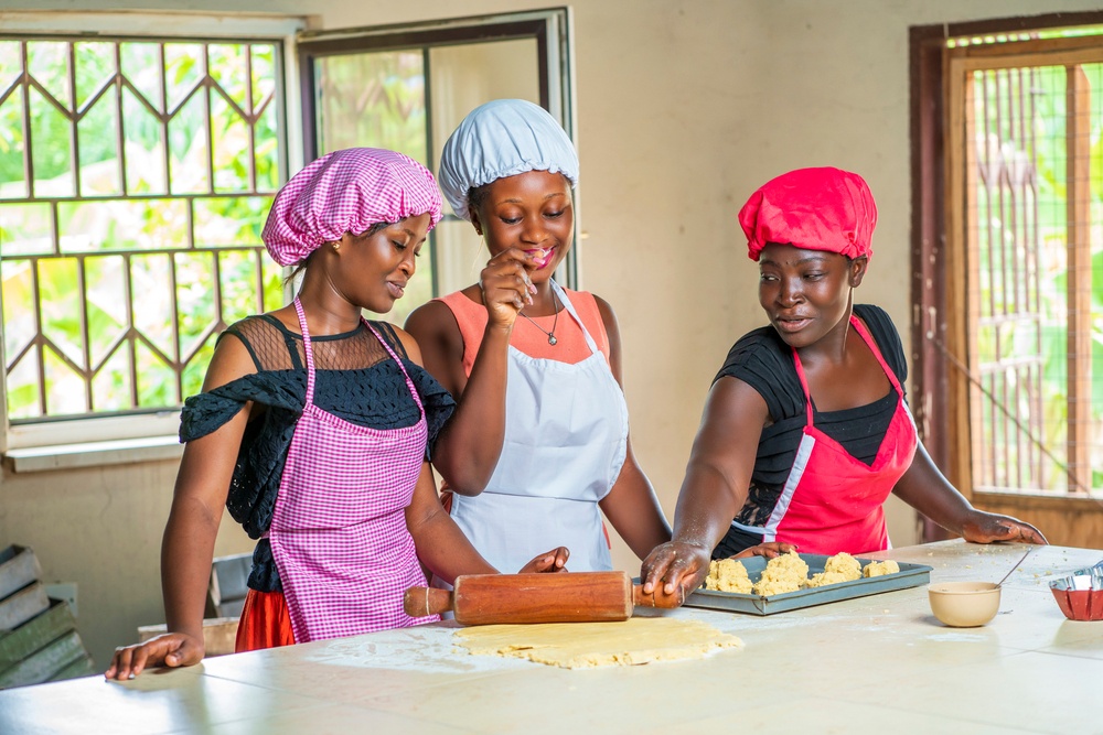 Three smiling women make cookies in a kitchen.