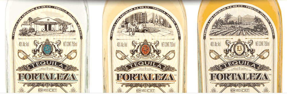 Three bottles of Tequila Fortaleza on a table: blanco, reposado, and anejo.