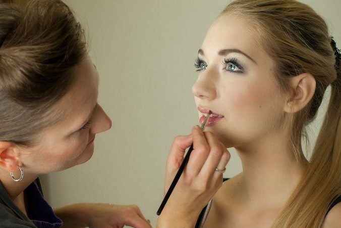 a makeup artist applies lipstick on a woman