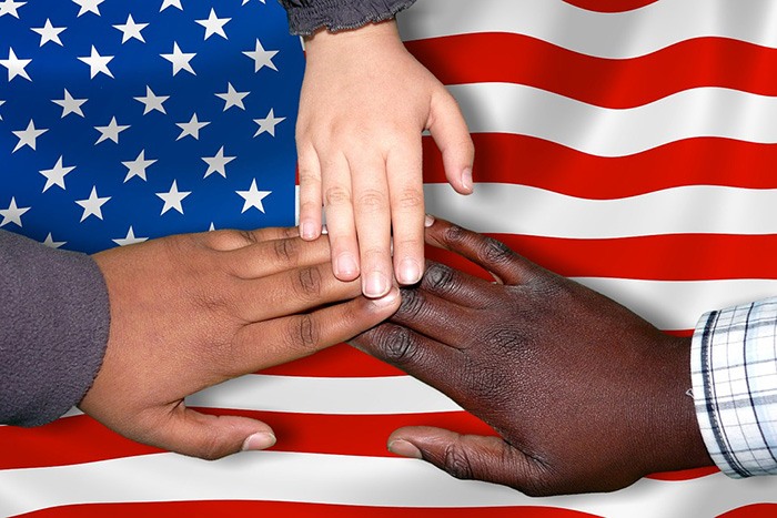 Three hands coming together over an American flag as an example of jobs for new immigrants