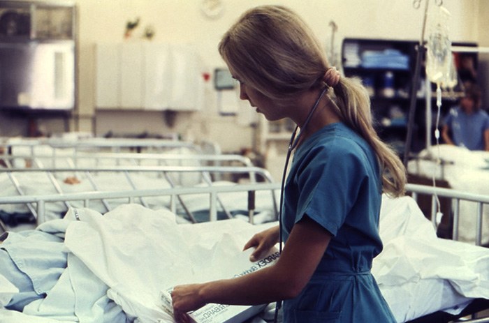 Picture of a woman working as a nurse changing the linen on a patients bed as an example of moonlighting jobs for nurses