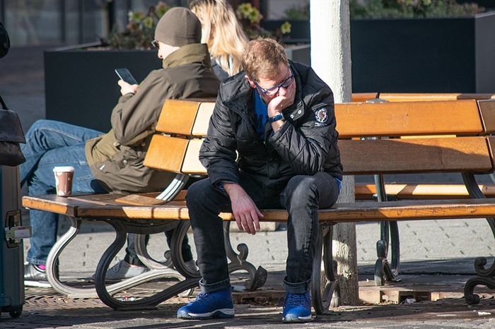 Man sitting on a park bench in distress representing an antisocial person