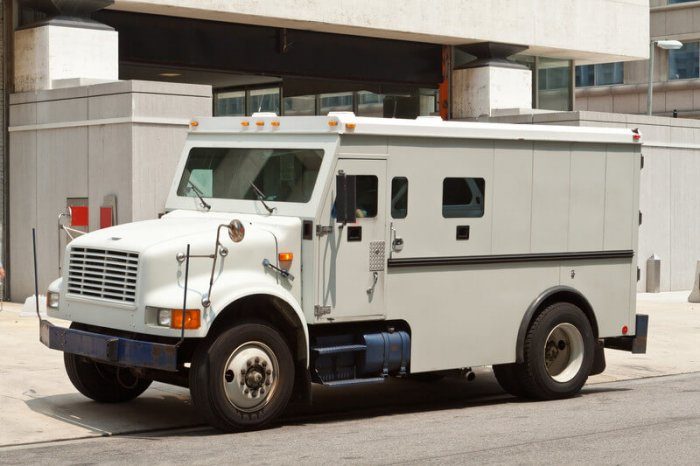 Picture of an armored car delivering money in front of a large building probably a hotel or bank