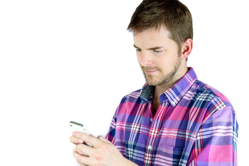 Young man using a cellphone isolated against a white background