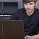 Image of a young man in a black shirt typing on a computer