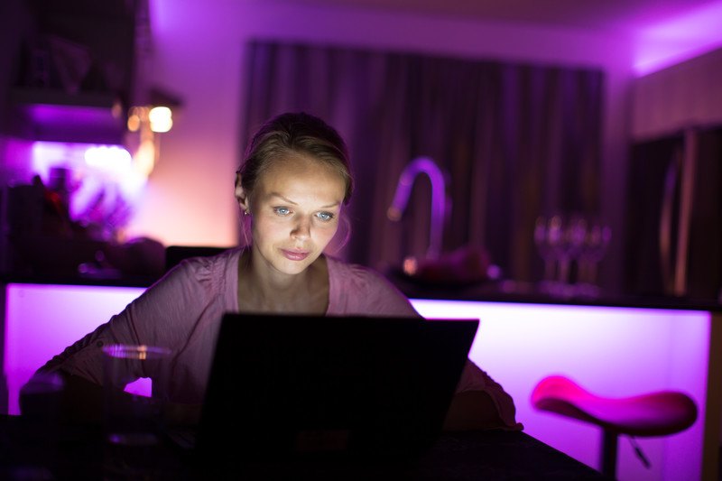 一位年轻女子晚上在紫色灯光的房间里使用笔记本电脑