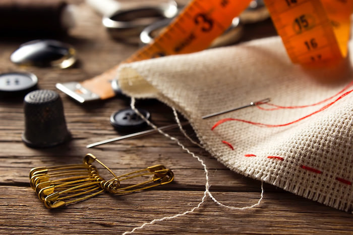 各种缝纫物品，包括布料、线轴、针和线在木桌子上，代表缝纫附属计划