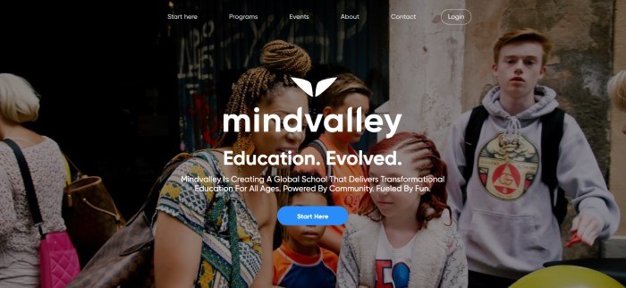 This screenshot of the home page for Mind Valley shows a dark-filtered photo of a woman talking with a few children, as the background to the white-lettered words, 