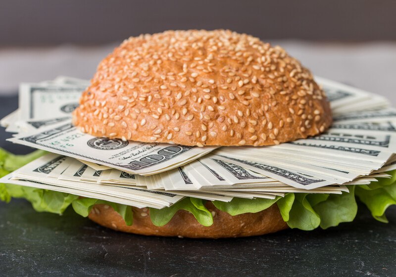hamburger bun with lettuce and hundred dollar bills instead of meat