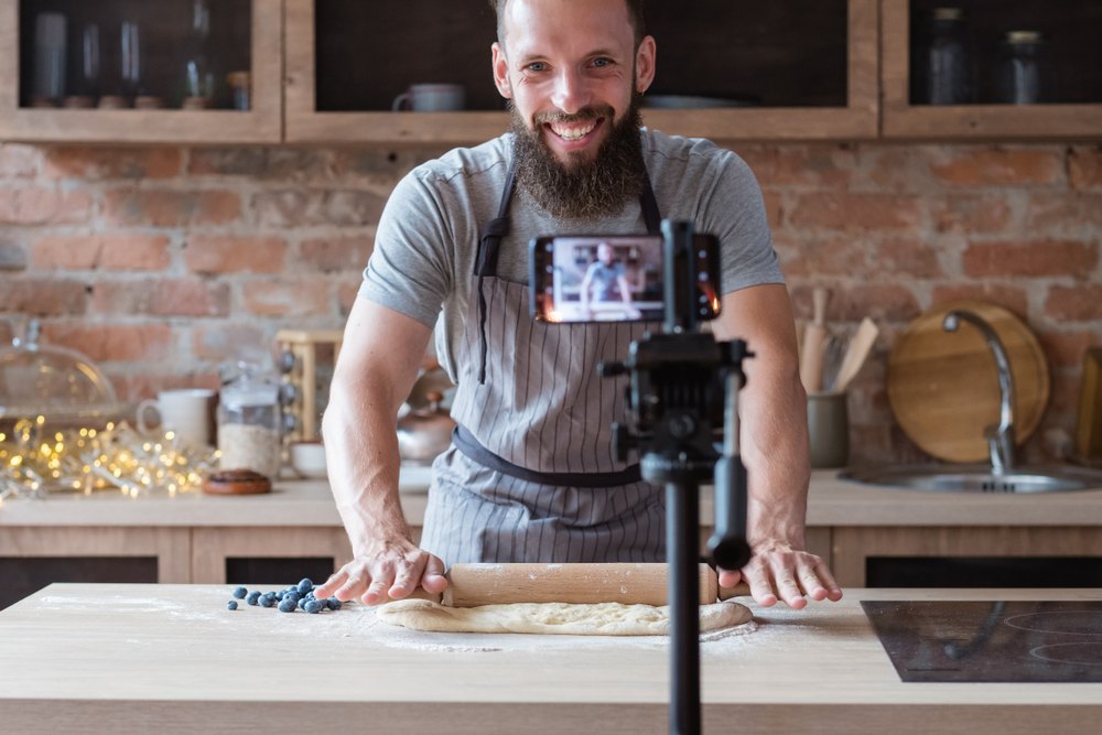 young man with beard filiming a food blog video on a smartphone