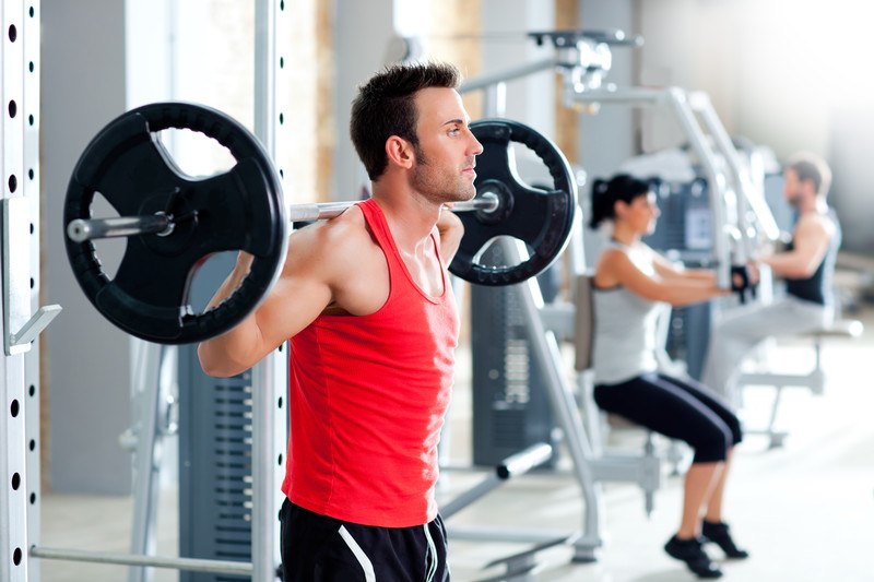 This image shows a man in a red shirt and a woman in a white shirt using workout equipment in what appears to be a gym full of fitness equipment, representing the best fitness equipment affiliate programs.