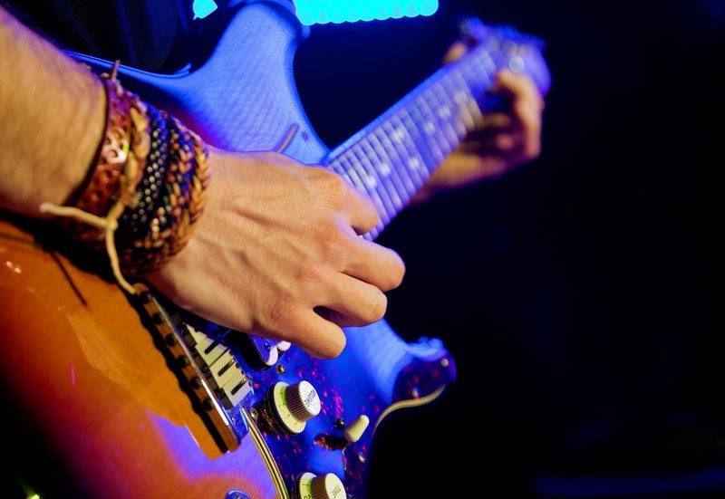 一个人手腕上戴着手镯弹吉他的特写