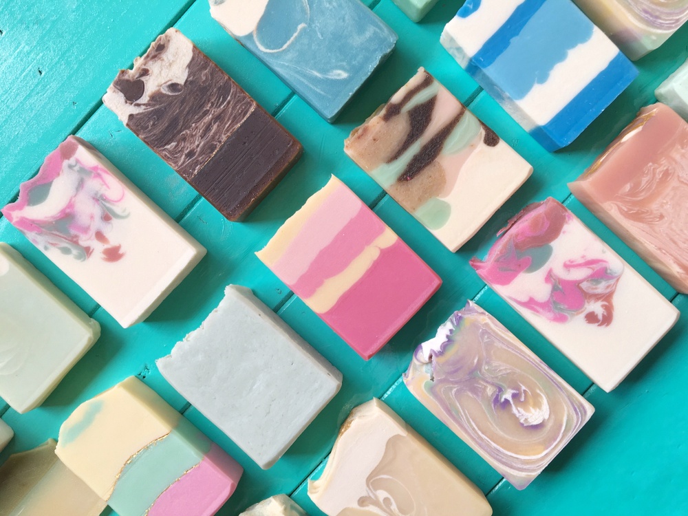 variety of homemade soaps with colors and patterns on blue wood table