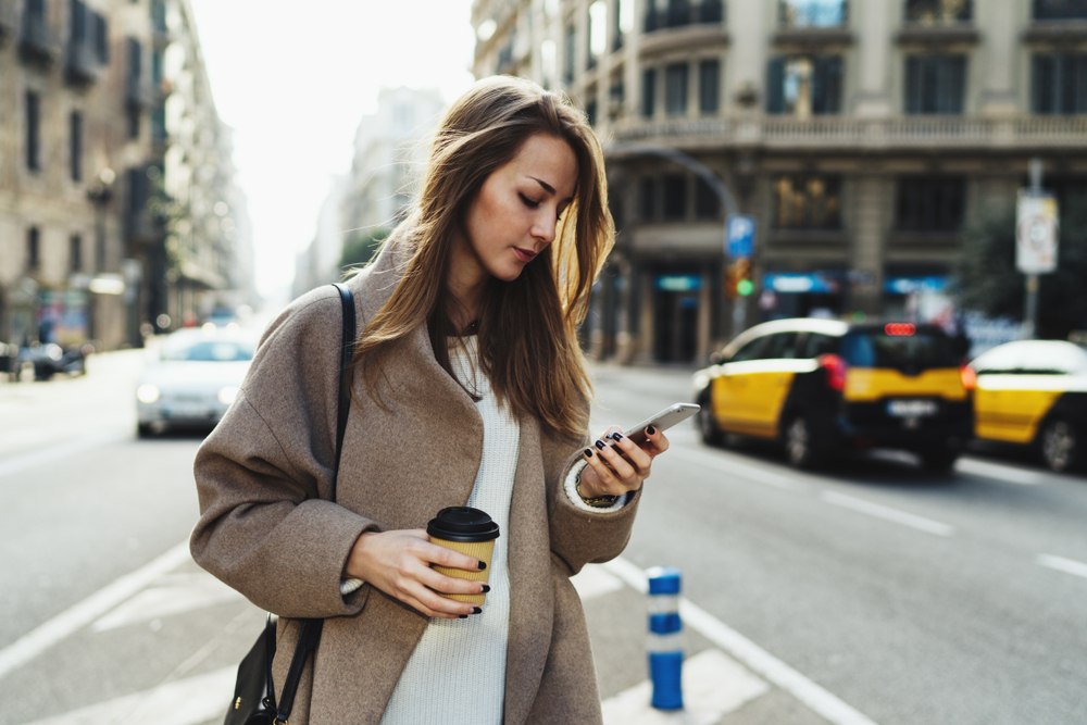 年轻女子在城市的车流中认真地看手机