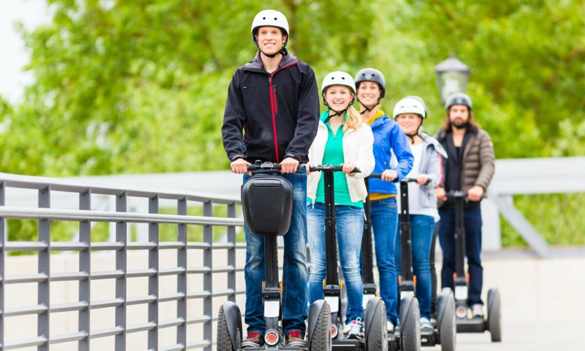 一个骑着赛格威的人带领着一群游客，他们也骑着赛格威。