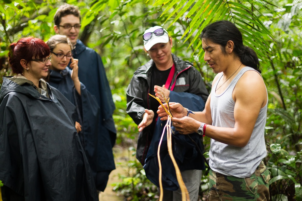 A tour guide shows a group of tourists how to braid a rope.
