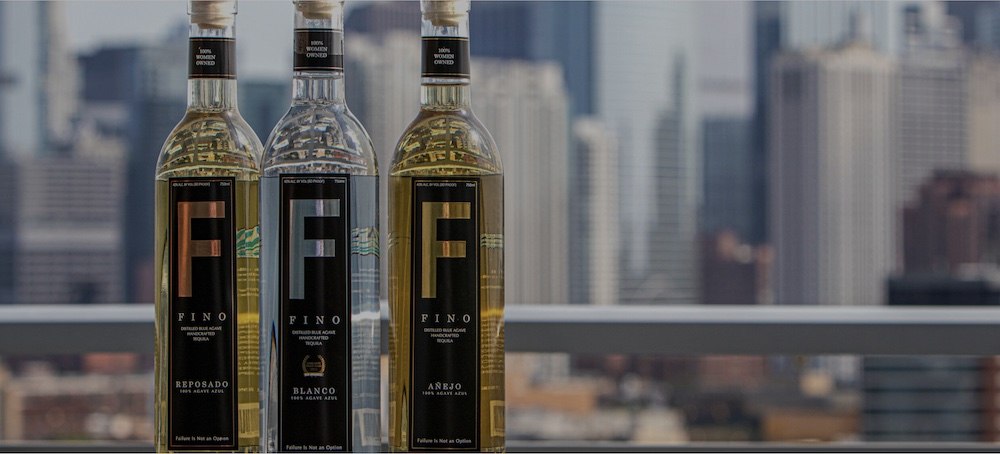 Three bottles of Fino Tequila sit on a balcony with the Los Angeles skyline in the background.