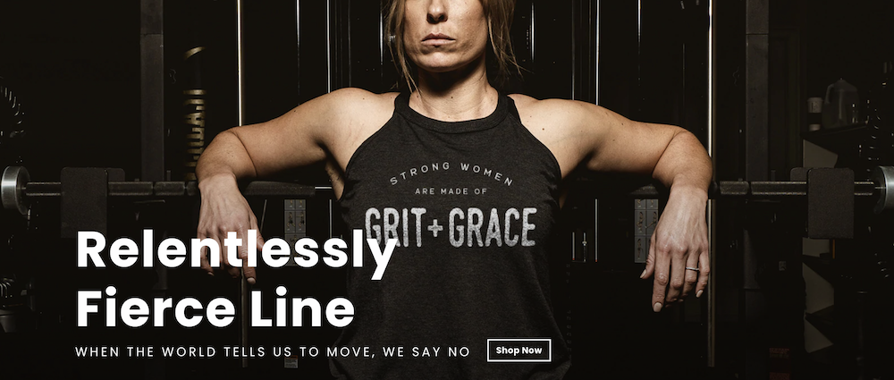 A physically fit woman leans back against a squat bar wearing a t-shirt that says 