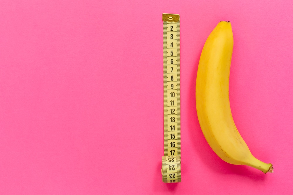新鲜香蕉在粉红色的背景与卷尺。一篇博客文章应该有多长?