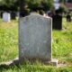 blank gravestone sitting in graveyard with overgrown grass
