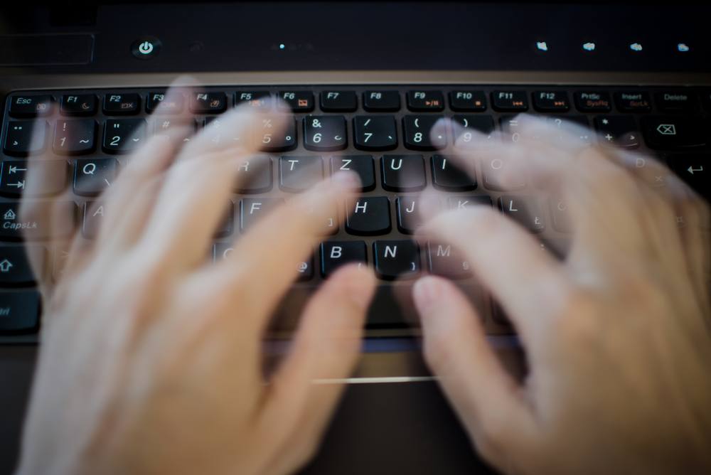模糊的手指在笔记本电脑键盘上快速打字