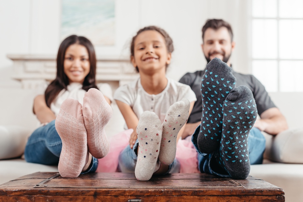 一个男人、女人和孩子把脚放在桌子上炫耀他们的新袜子。