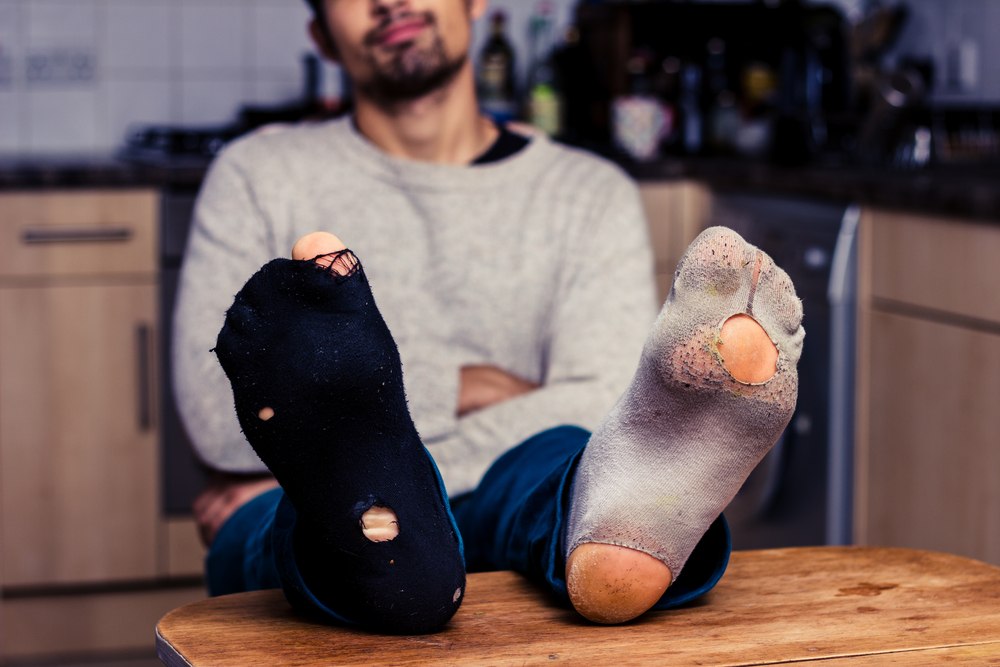 一个男人穿着不相配的有洞的袜子。