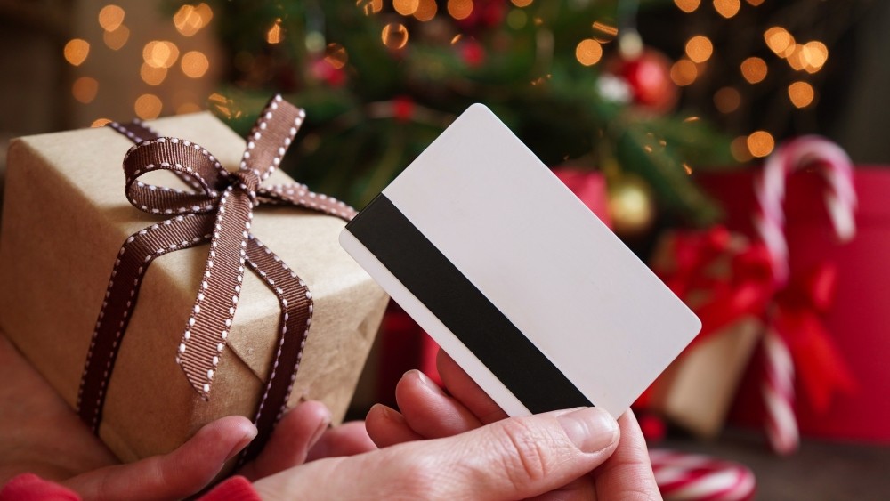 Holding a gift card in one hand and a present in the other