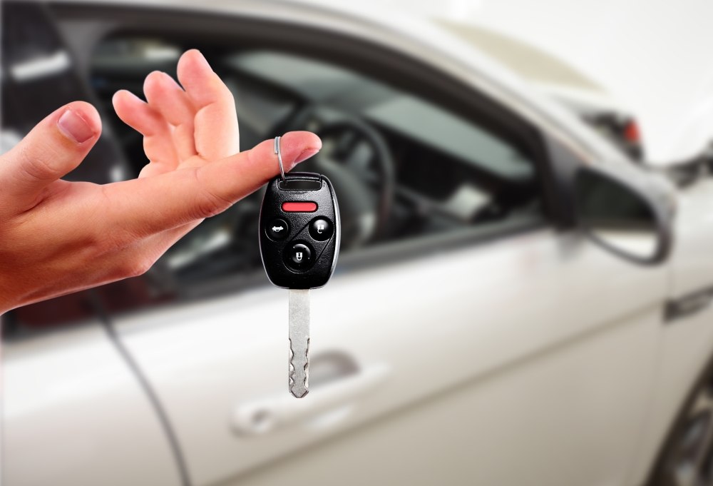 Person holding a car key in front of a car
