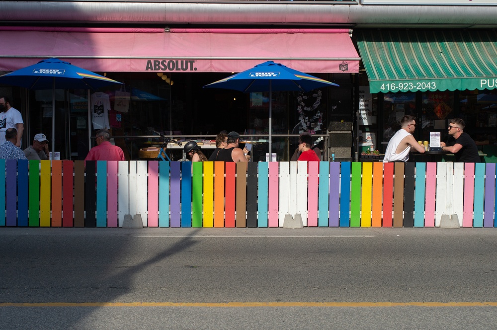 picket fence around restaurant dining area painted with lgbtq flag colors