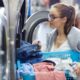 woman looking into laundry machine with load of laundry at laundromat