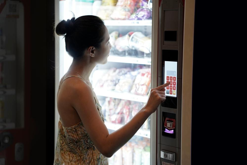 Woman standing in front of vending machine putting money into the machine