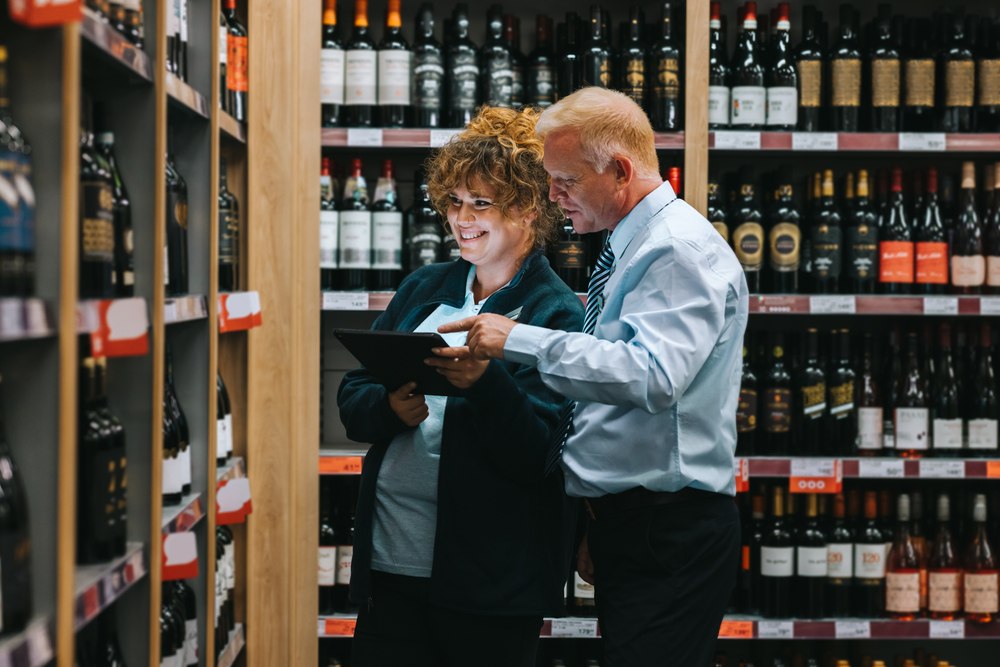 liquor store owner taking inventory in his shop with an employee